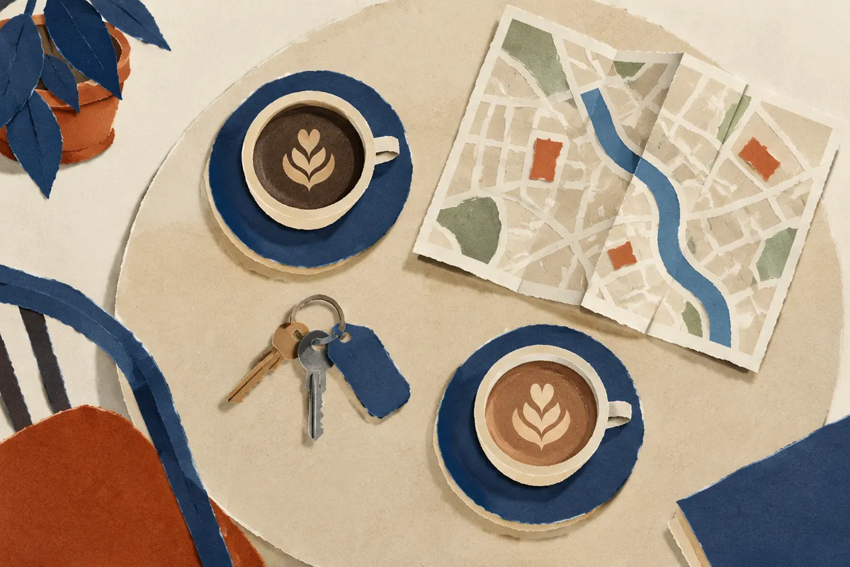 Mesa de café con dos tazas, un mapa de la ciudad y unas llaves vista desde arriba